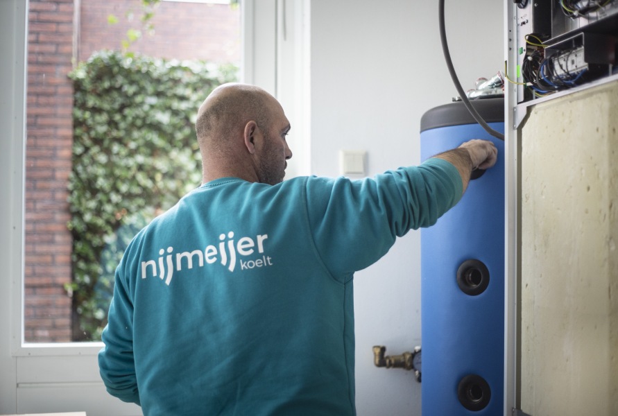 Een monteur van Nijmeijer Koelt is druk in de weer met de installatie van een warmtepomp.