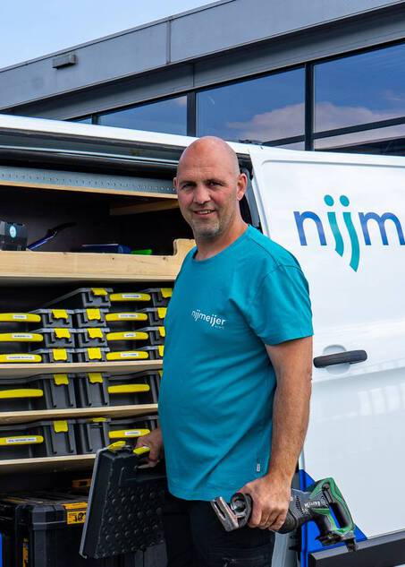 Projectleider koeltechniek met gereedschap naast een servicebus van Nijmeijer Koelt.